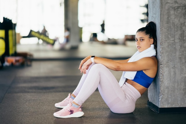 Mujer joven sana sentada relajada después de entrenar en el gimnasio