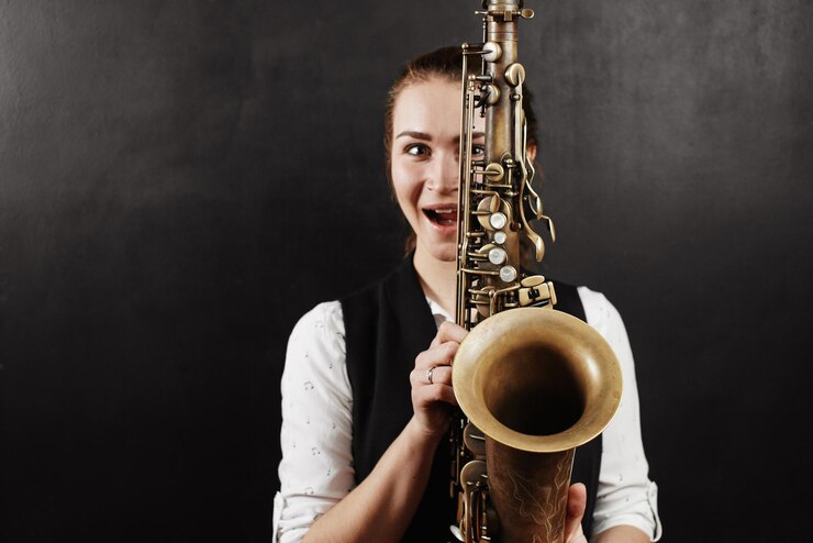 Foto mujer joven con saxofón sobre fondo negro