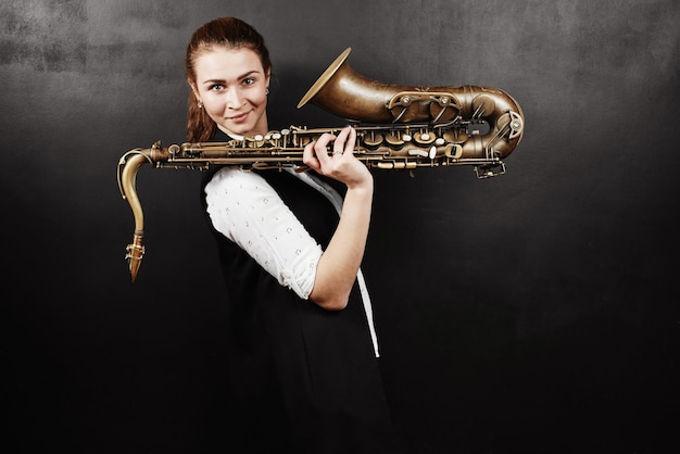 Mujer joven con saxofón sobre fondo negro