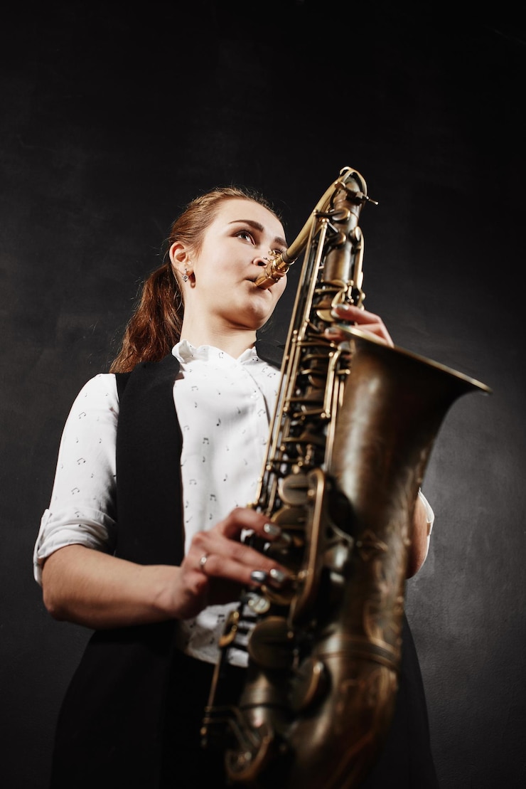 Foto mujer joven con saxofón sobre fondo negro