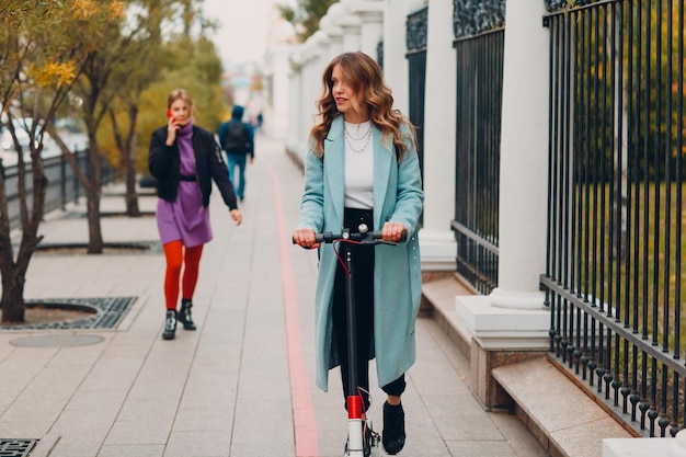 Mujer joven con scooter eléctrico en la ciudad