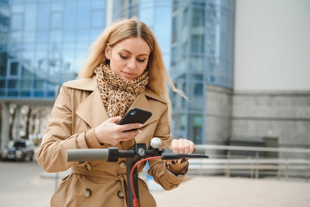 Mujer joven con scooter eléctrico en la ciudad