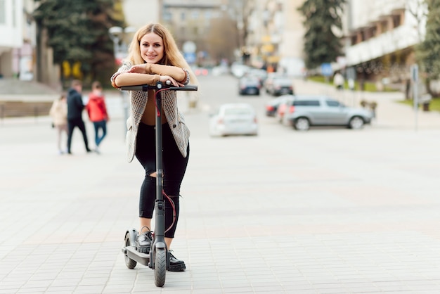 Mujer joven con scooter eléctrico en la ciudad