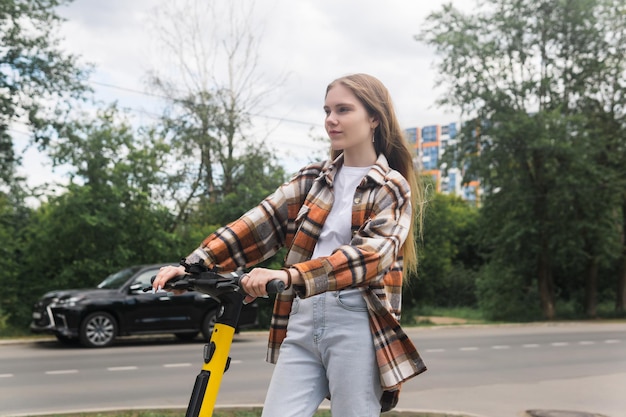 Una mujer joven en un scooter eléctrico viaja por la calle