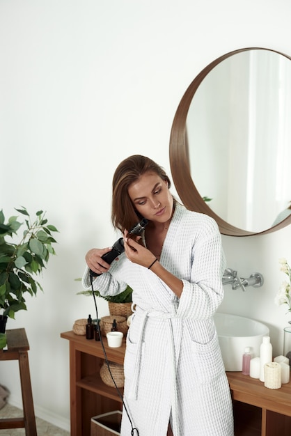 Foto mujer joven secar el cabello en el baño. estilo de belleza