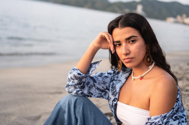 Mujer joven sentada en la arena junto a la orilla de la playa