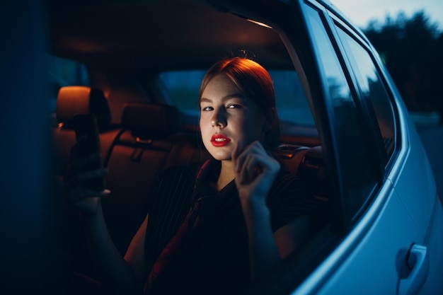 Mujer joven sentada en el asiento trasero del vehículo del automóvil por la noche Concepto de taxi