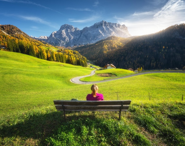 Mujer joven sentada en el banco y hermoso pueblo alpino