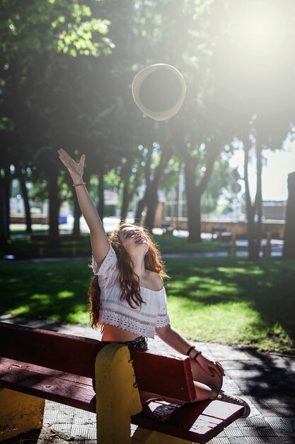 Foto mujer joven sentada en un banco en el parque durante un día soleado