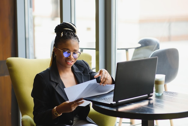 Mujer joven sentada en un café trabajando en un portátil.