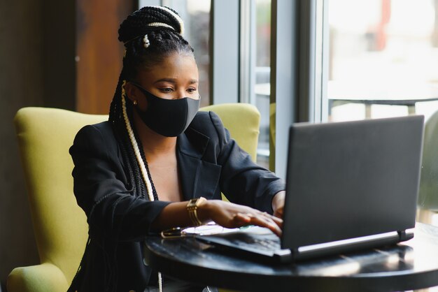 Mujer joven sentada en un café trabajando en un portátil.