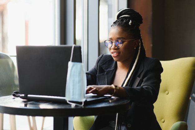 Mujer joven sentada en un café trabajando en un portátil.