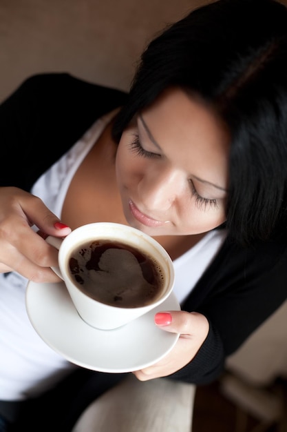 Mujer joven sentada en una cafetería tomando café