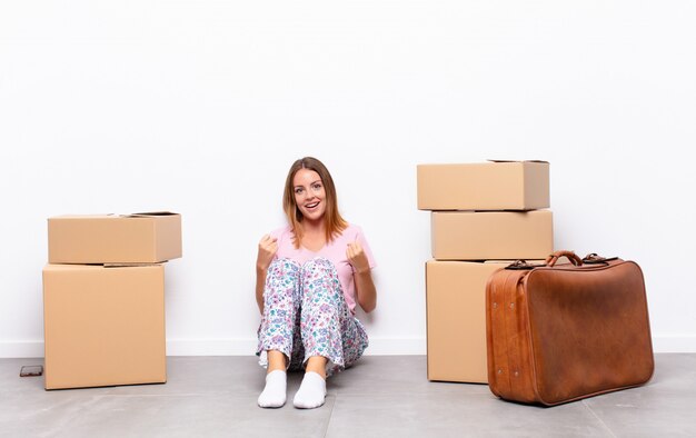 mujer joven sentada entre cajas gritando triunfante