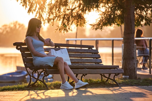 Mujer joven sentada en la calle de la ciudad sola esperando que alguien llegue Llegar tarde al concepto de reunión de fecha