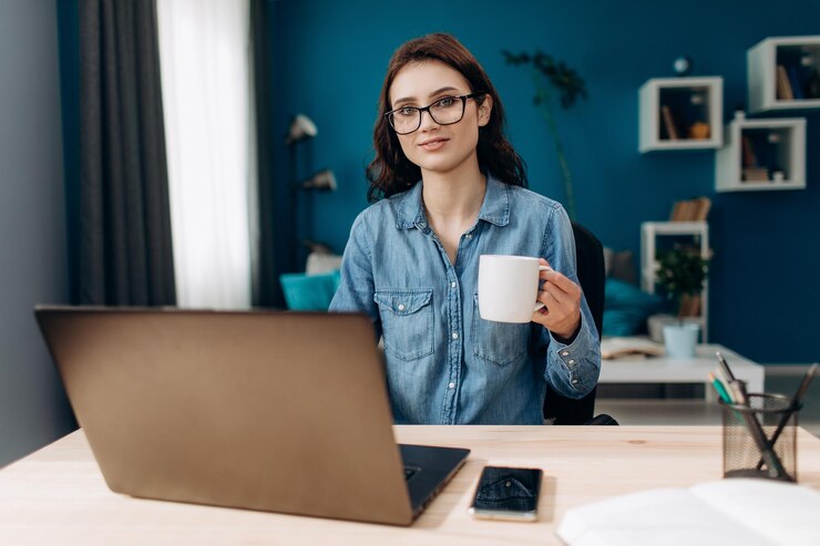 Mujer joven sentada en casa con laptop y café caliente