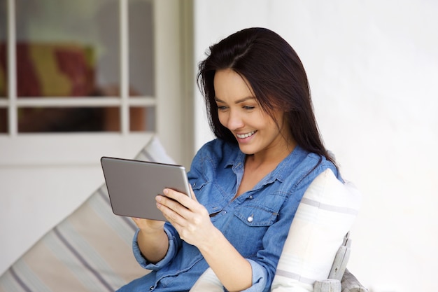 Mujer joven sentada en casa con tableta digital