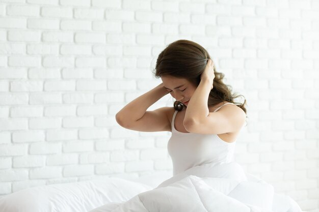 Mujer joven sentada contra la pared blanca