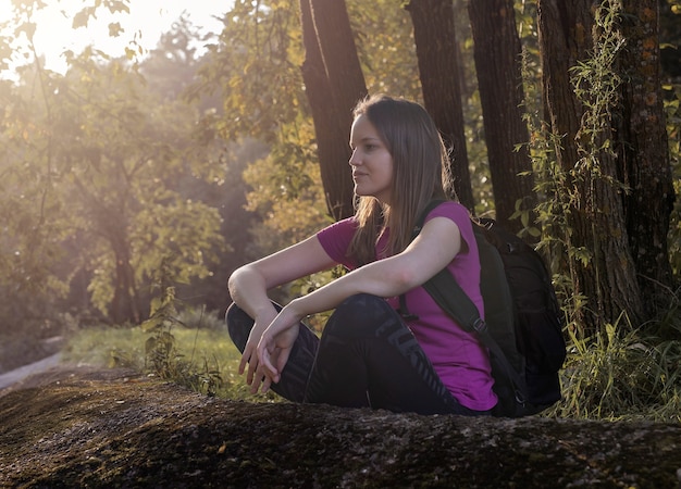 Mujer joven sentada descansando y disfrutando de la naturaleza solo después de caminar al aire libre mochilero femenino