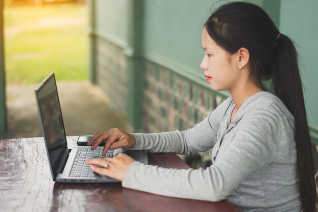 Foto una mujer joven sentada en el escritorio de su casa y respondiendo al chat del cliente en una pequeña empresa portátil en casa y chateando en línea concepto de redes sociales espacio de copia para texto individual