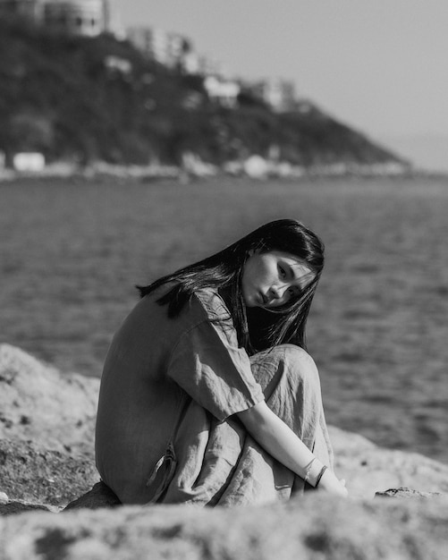 Mujer joven sentada en una formación rocosa contra el cielo