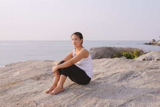 Mujer joven sentada en el mar al amanecer