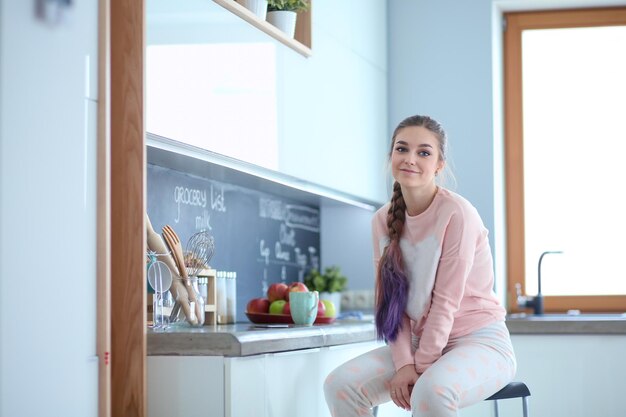 Mujer joven sentada en la mesa en la cocina