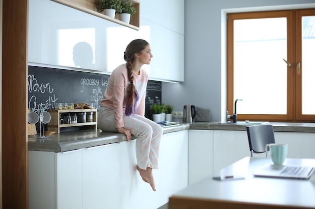 Mujer joven sentada en la mesa en la cocina