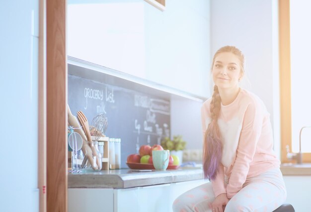 Mujer joven sentada en la mesa en la cocina