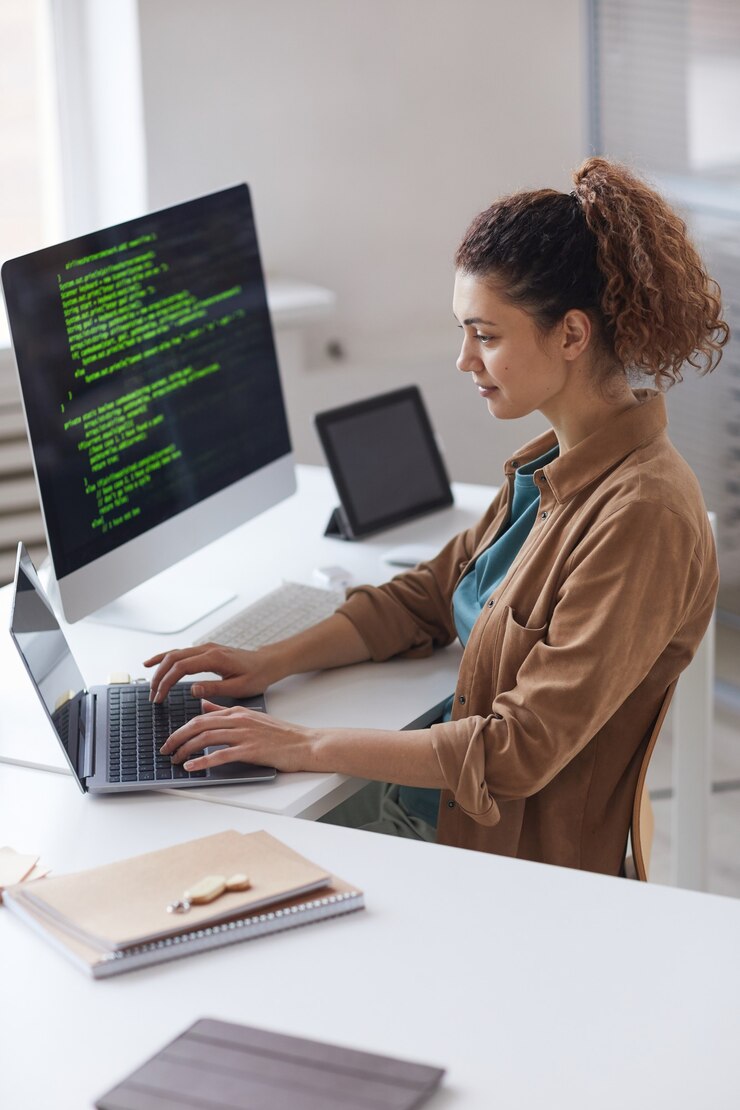 Foto mujer joven sentada en la mesa y concentrándose en el trabajo en línea en la computadora portátil que trabaja en el servicio informático