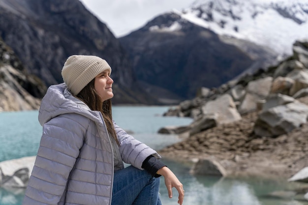Mujer joven sentada mientras contempla un paisaje pintoresco con un lago