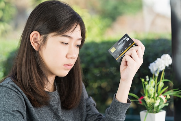 Mujer joven sentada mostrando tarjeta de crédito