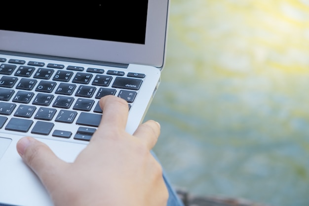 Mujer joven sentada en el muelle con la computadora portátil