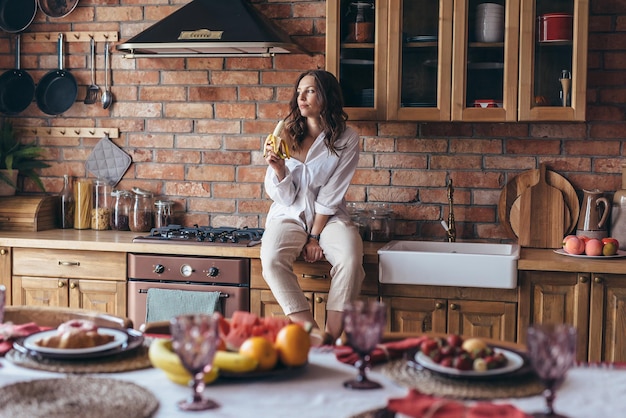 Mujer joven sentada con un plátano en la cocina sobre la mesa