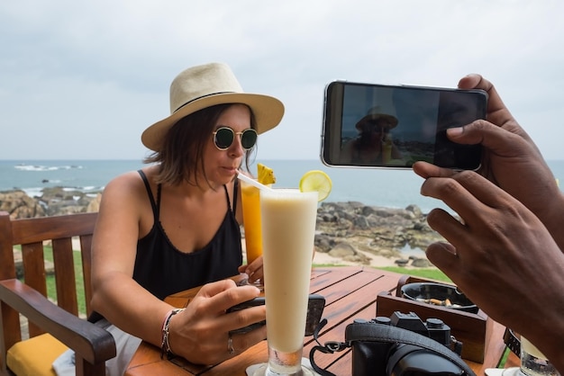 Mujer joven sentada en el restaurante bebiendo jugo y esperando comida