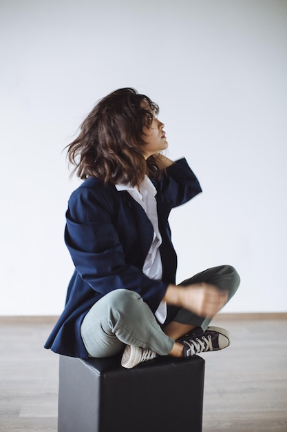 Foto mujer joven sentada en una silla contra la pared