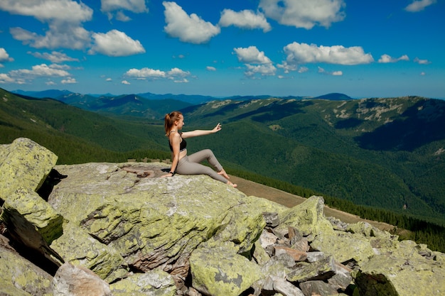 Foto mujer joven sentada sobre una roca y mirando al horizonte