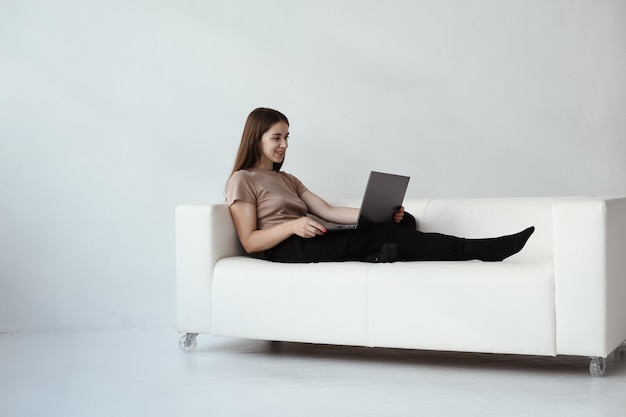 Mujer joven sentada en un sofá con una computadora portátil Concepto de sesión en línea con un psicólogo