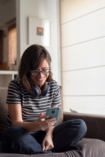 Foto mujer joven sentada en un sofá con un teléfono móvil