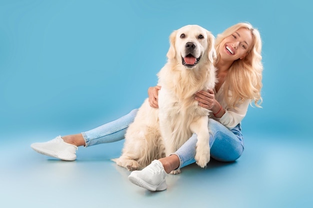 Mujer joven sentada con su perro en blue studio