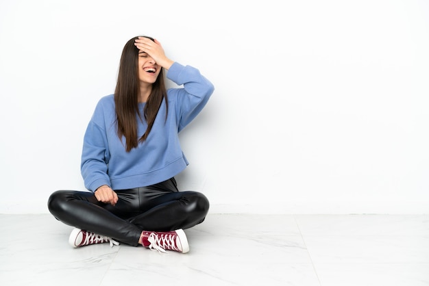 Mujer joven sentada en el suelo aislado sobre fondo blanco se ha dado cuenta de algo y tiene la intención de la solución