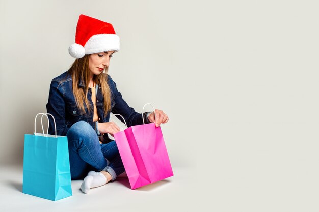 Mujer joven sentada en el suelo junto a bolsas de compras