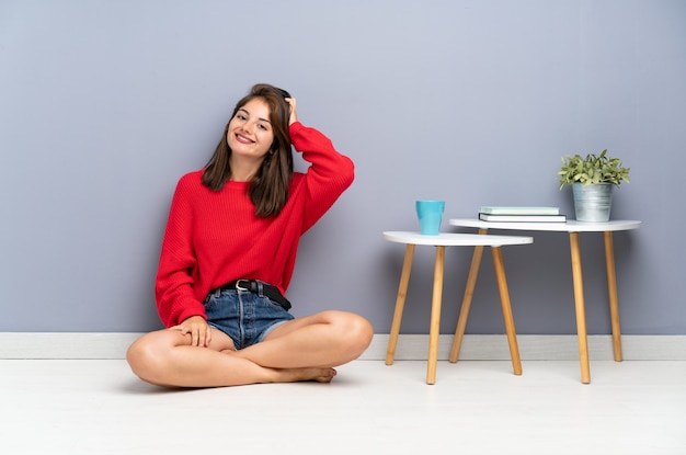 Mujer joven sentada en el suelo riendo