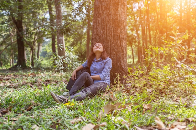 Foto mujer joven sentada en el tronco de un árbol en el bosque