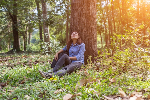 Foto mujer joven sentada en el tronco de un árbol en el bosque