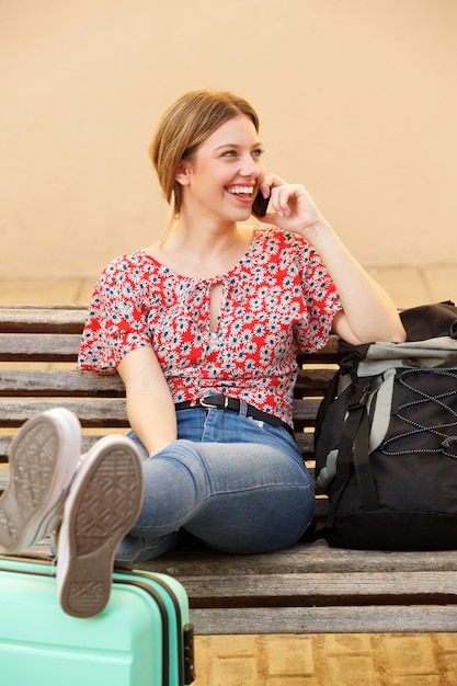 mujer joven, sentado, en, banco, con, maleta, hablar celular