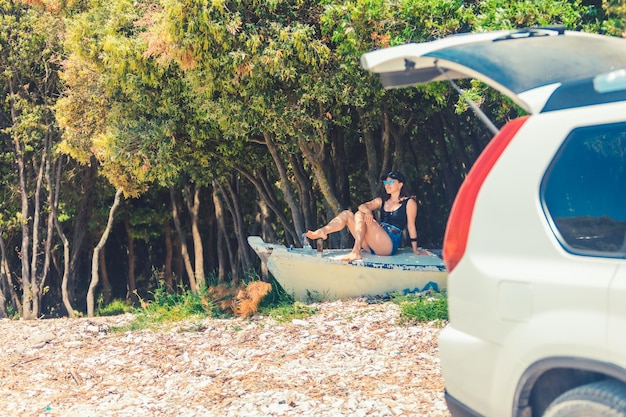 mujer joven, sentado, en, barco, en, playa, cerca, coche