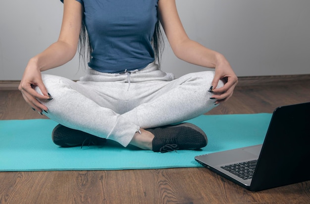 mujer joven, sentado, en, colchoneta del ejercicio, delante de, computador portatil