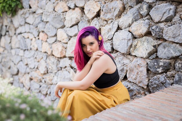 mujer joven, sentado, en, pared de piedra