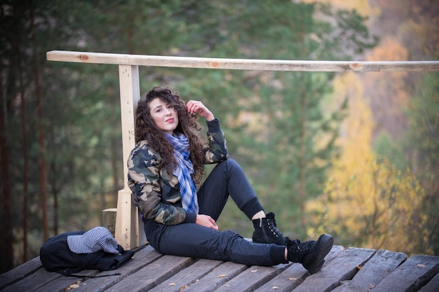 mujer joven, sentado, en, un, plataforma, en, un, plano de fondo, de, el, bosque